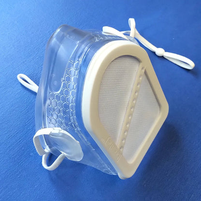 Picture of a clear [breathe] mask with a white filter, against a blue background.